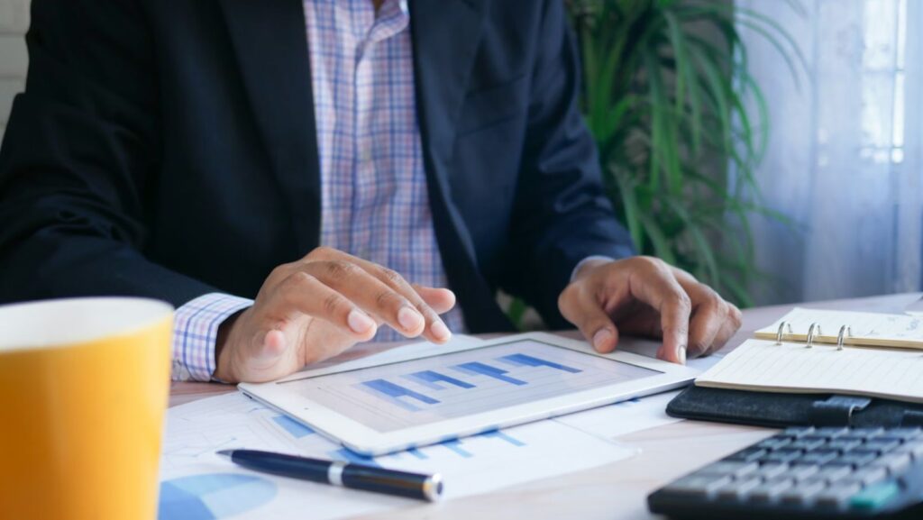 : Person holding tablet displaying data, symbolizing analytics in sports and finance decisions.